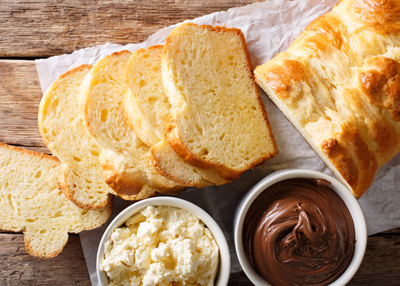 sliced brioche bread with bowls of cream cheese and chocolate spread on a wooden table perfect for breakfast or dessert with 7 delicious options